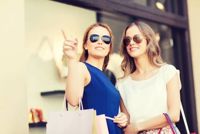 sale-consumerism-people-concept-happy-young-women-with-shopping-bags-pointing-finger-shop-window-city (1)